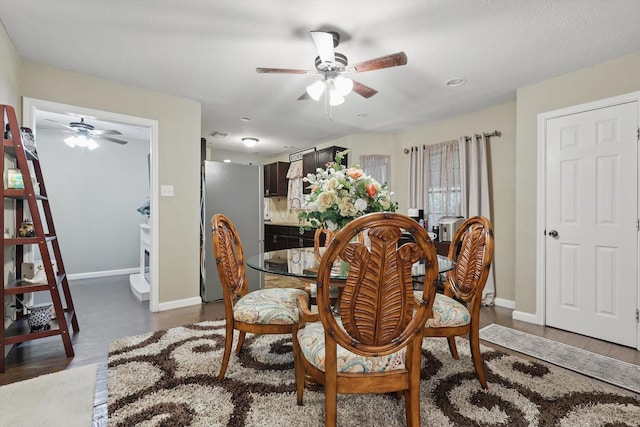 dining area featuring a ceiling fan, baseboards, and dark wood-style flooring