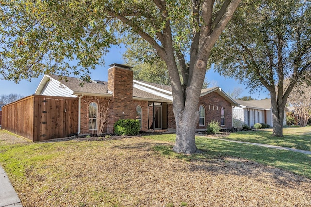 ranch-style house featuring a front lawn, brick siding, roof with shingles, and a chimney