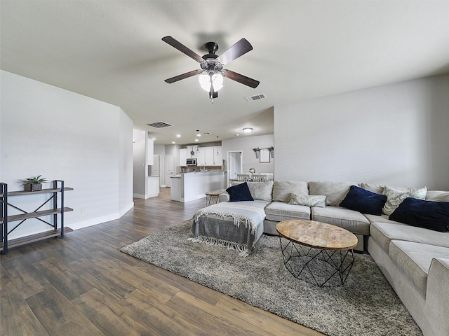 living room featuring baseboards, visible vents, dark wood finished floors, and a ceiling fan