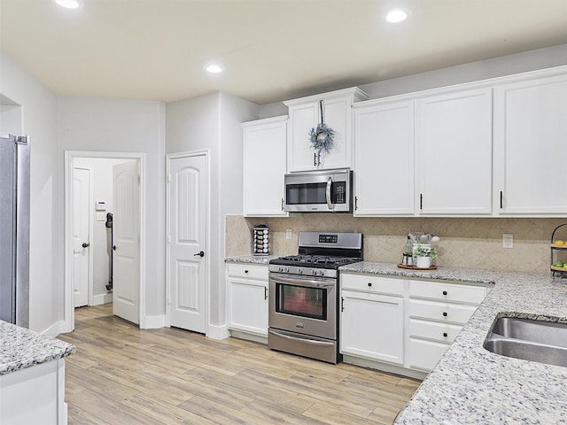 kitchen featuring recessed lighting, stainless steel appliances, white cabinets, light wood-style floors, and tasteful backsplash