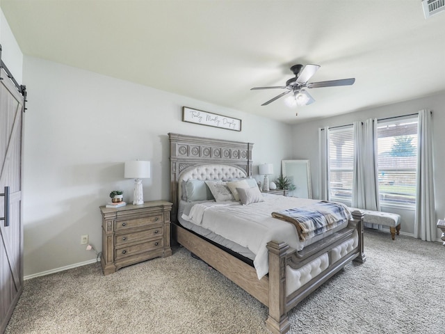 bedroom with light colored carpet, visible vents, a barn door, a ceiling fan, and baseboards