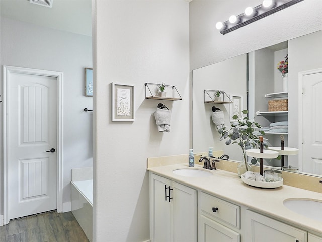 bathroom with double vanity, visible vents, a sink, and wood finished floors