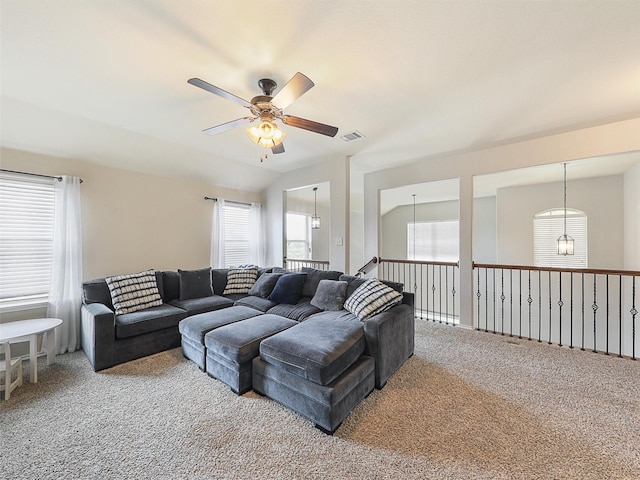 living area featuring visible vents, vaulted ceiling, carpet flooring, and ceiling fan with notable chandelier