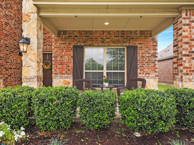 entrance to property featuring covered porch and brick siding