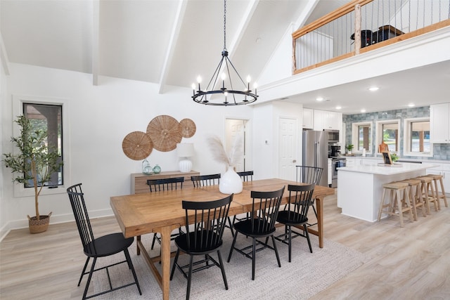 dining room with light wood finished floors, a chandelier, high vaulted ceiling, beamed ceiling, and baseboards