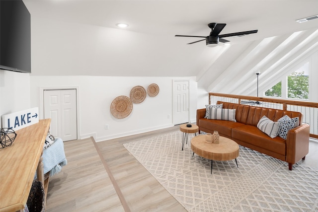 living area featuring a ceiling fan, visible vents, vaulted ceiling, and light wood finished floors