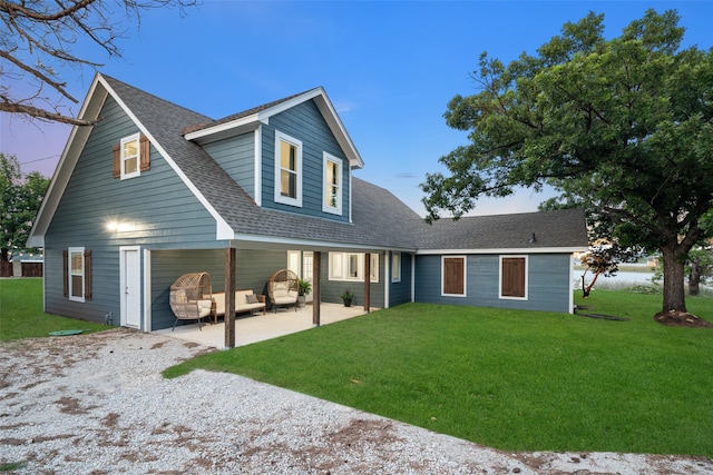 view of front of property with a shingled roof, a patio area, and a front yard