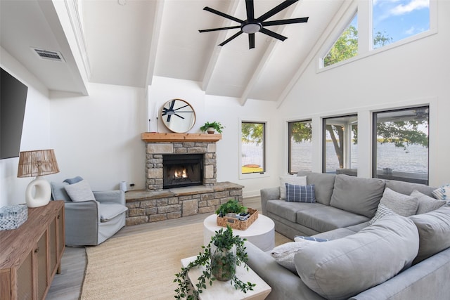 living room with wood finished floors, beamed ceiling, a fireplace, high vaulted ceiling, and a wealth of natural light