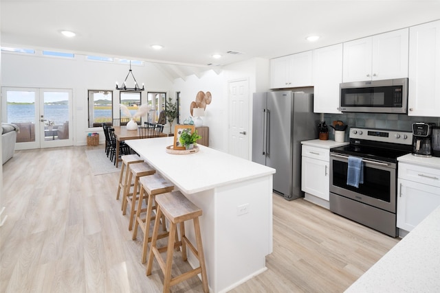 kitchen with a chandelier, light countertops, appliances with stainless steel finishes, and a breakfast bar