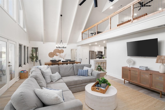 living room featuring light wood finished floors, high vaulted ceiling, a chandelier, and french doors