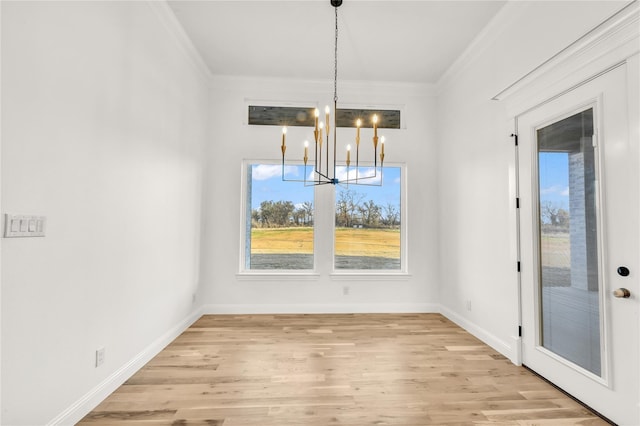 unfurnished dining area featuring baseboards, crown molding, a notable chandelier, and light wood finished floors