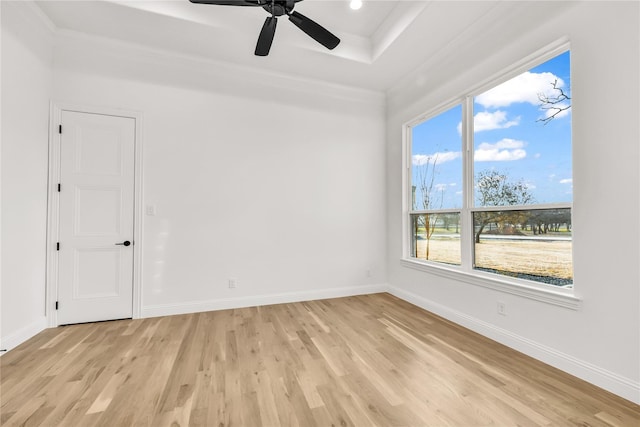 unfurnished room featuring ornamental molding, a tray ceiling, light wood-style floors, and baseboards