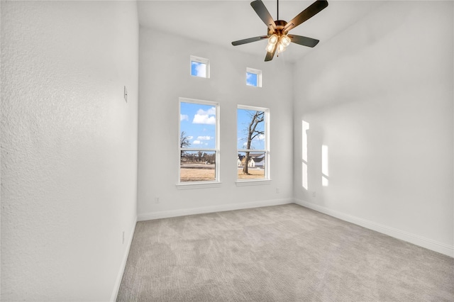 spare room featuring carpet floors, a ceiling fan, and baseboards