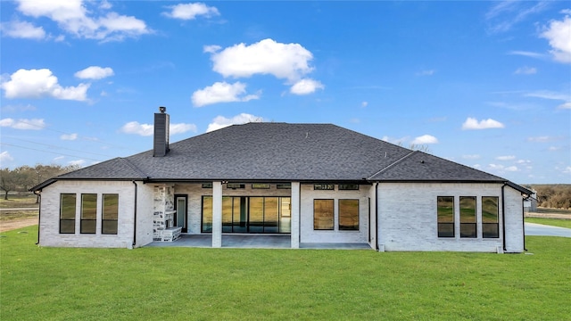 rear view of house featuring a yard, brick siding, a chimney, and a patio area