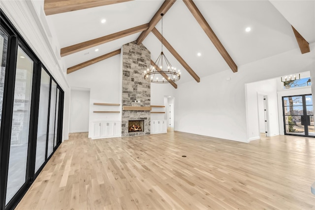 unfurnished living room featuring high vaulted ceiling, light wood-style floors, a fireplace, and a notable chandelier