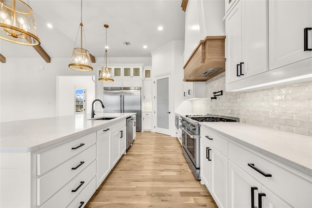 kitchen featuring stainless steel appliances, decorative backsplash, light wood-style floors, glass insert cabinets, and a sink