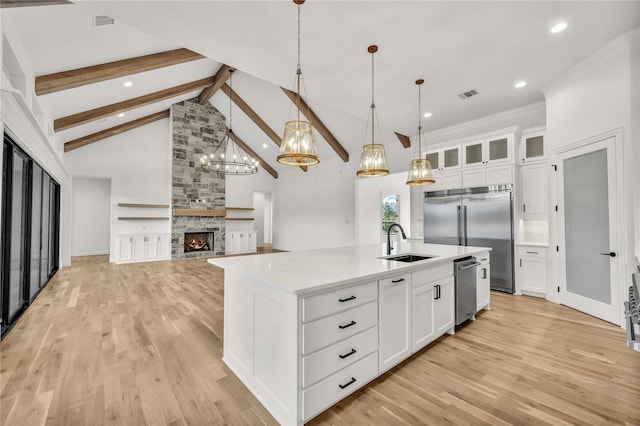 kitchen with stainless steel appliances, a sink, visible vents, light wood-type flooring, and beamed ceiling