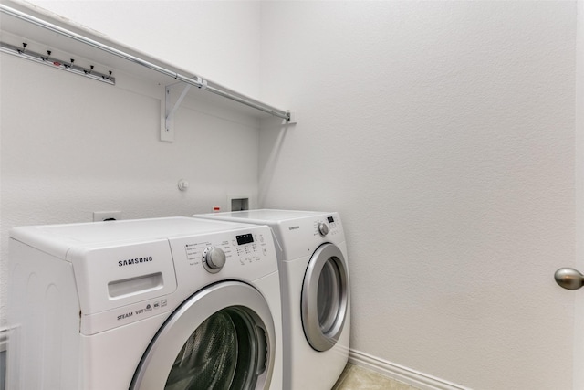 clothes washing area with laundry area, washer and clothes dryer, and baseboards