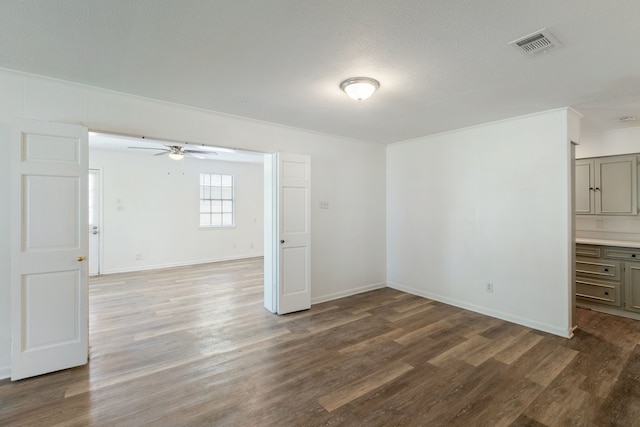 empty room featuring a ceiling fan, visible vents, baseboards, and wood finished floors