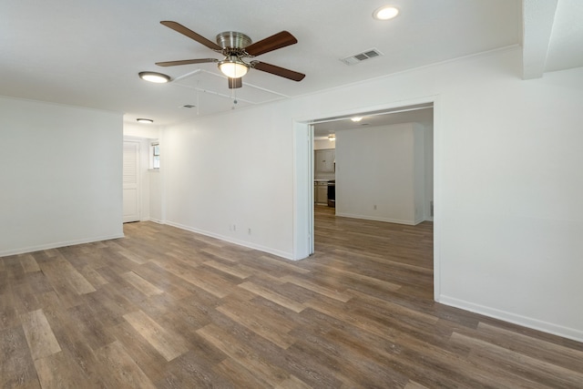 spare room featuring baseboards, visible vents, ceiling fan, and wood finished floors