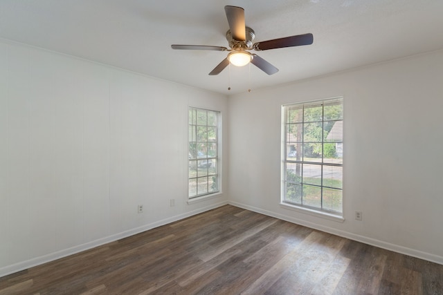 spare room featuring ceiling fan, plenty of natural light, baseboards, and dark wood finished floors