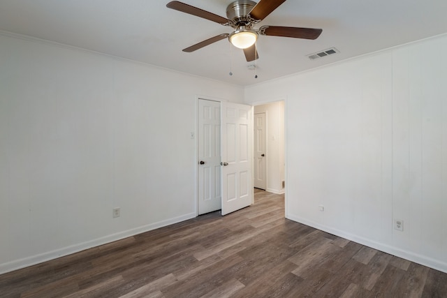 spare room with baseboards, dark wood finished floors, visible vents, and crown molding