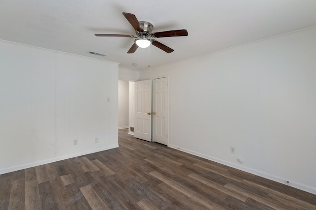 empty room with crown molding, visible vents, dark wood-type flooring, ceiling fan, and baseboards