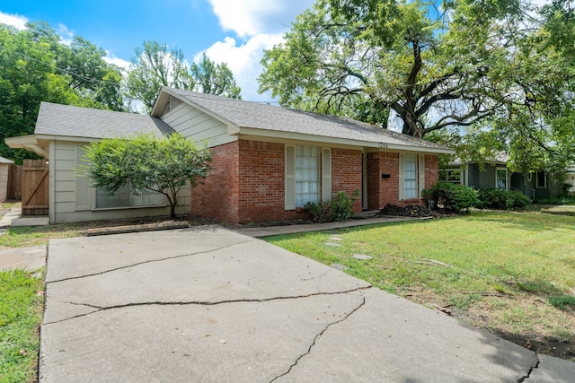 ranch-style house with driveway, brick siding, and a front lawn