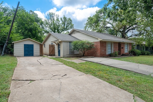 single story home with an outbuilding, brick siding, concrete driveway, a front yard, and a garage