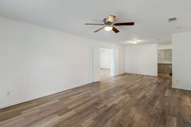 interior space featuring baseboards, visible vents, ceiling fan, and wood finished floors