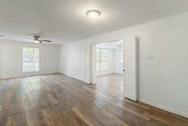 unfurnished room with a textured ceiling, ceiling fan, plenty of natural light, and wood finished floors