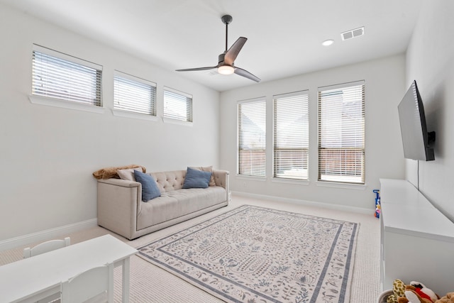 carpeted living room with baseboards, a wealth of natural light, visible vents, and a ceiling fan