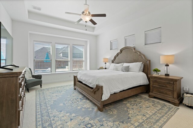 bedroom featuring carpet floors, ceiling fan, visible vents, and a raised ceiling