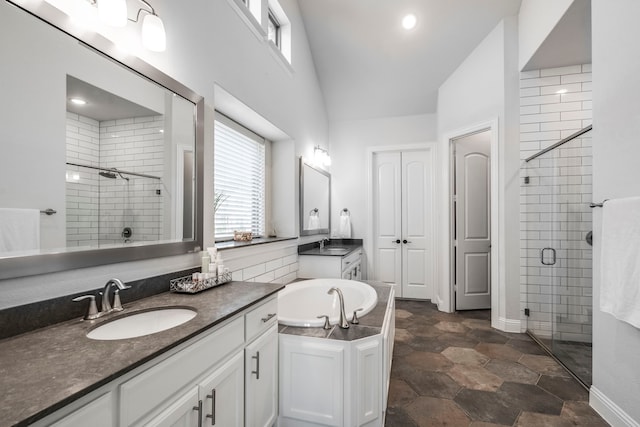 bathroom with a stall shower, a garden tub, two vanities, and a sink