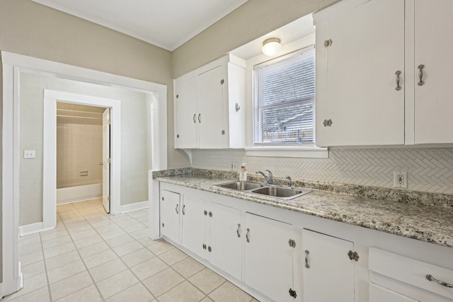 kitchen featuring light tile patterned floors, white cabinets, decorative backsplash, light countertops, and a sink