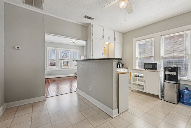 kitchen with ceiling fan, visible vents, black microwave, and white cabinets