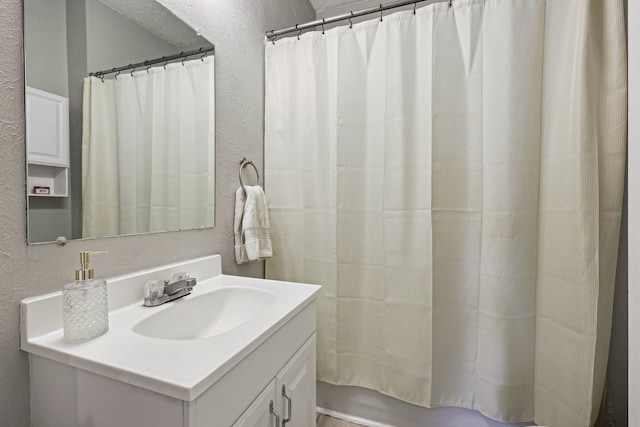 bathroom with a shower with shower curtain, vanity, and a textured wall