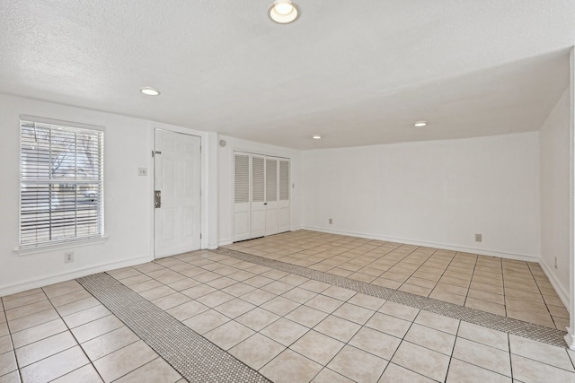 foyer featuring light tile patterned floors, a textured ceiling, baseboards, and recessed lighting