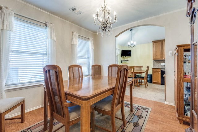 dining space featuring a chandelier, arched walkways, visible vents, and light wood-style floors