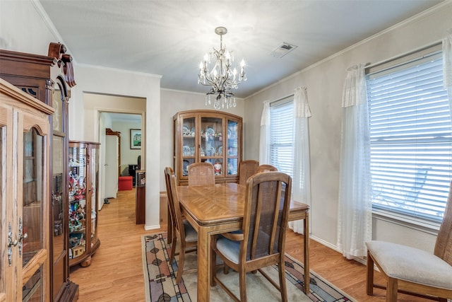 dining space featuring light wood finished floors, visible vents, ornamental molding, and an inviting chandelier