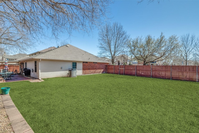 view of yard with a fenced backyard, central AC, and a patio