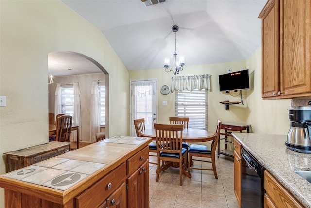 kitchen featuring black dishwasher, tile counters, brown cabinetry, arched walkways, and vaulted ceiling