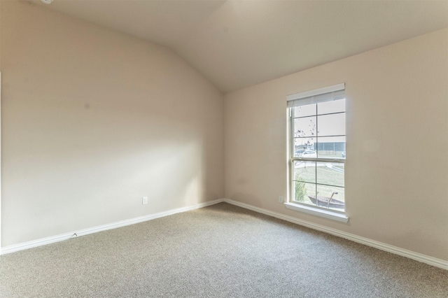 carpeted spare room featuring vaulted ceiling and baseboards