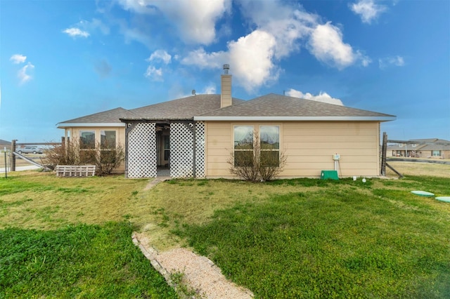 rear view of property featuring a lawn, a chimney, and fence