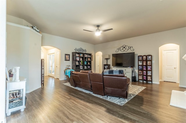 living room featuring a ceiling fan, arched walkways, baseboards, and wood finished floors