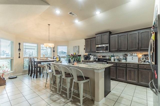 kitchen featuring a kitchen island with sink, visible vents, dark brown cabinets, appliances with stainless steel finishes, and backsplash