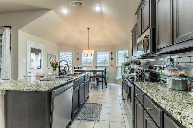 kitchen with a center island with sink, visible vents, appliances with stainless steel finishes, a sink, and light tile patterned flooring