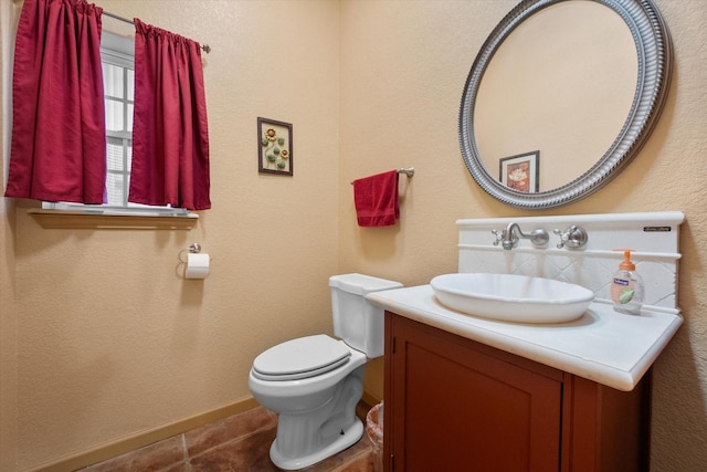 bathroom featuring baseboards, vanity, toilet, and tile patterned floors