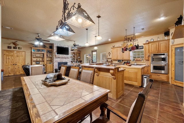 dining space featuring visible vents, ornamental molding, a stone fireplace, a textured ceiling, and dark tile patterned flooring