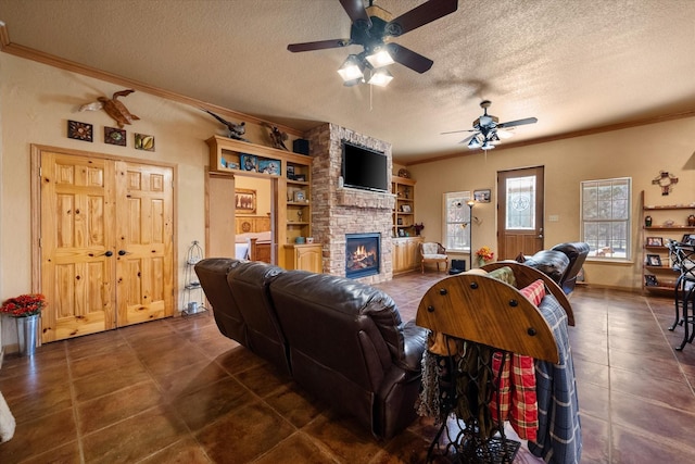 living room with a ceiling fan, dark tile patterned flooring, a stone fireplace, crown molding, and a textured ceiling